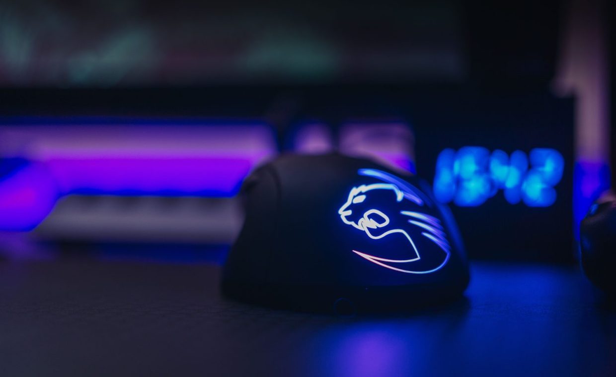 Close-up of an illuminated gaming mouse with LED lights on a dark desk setting.