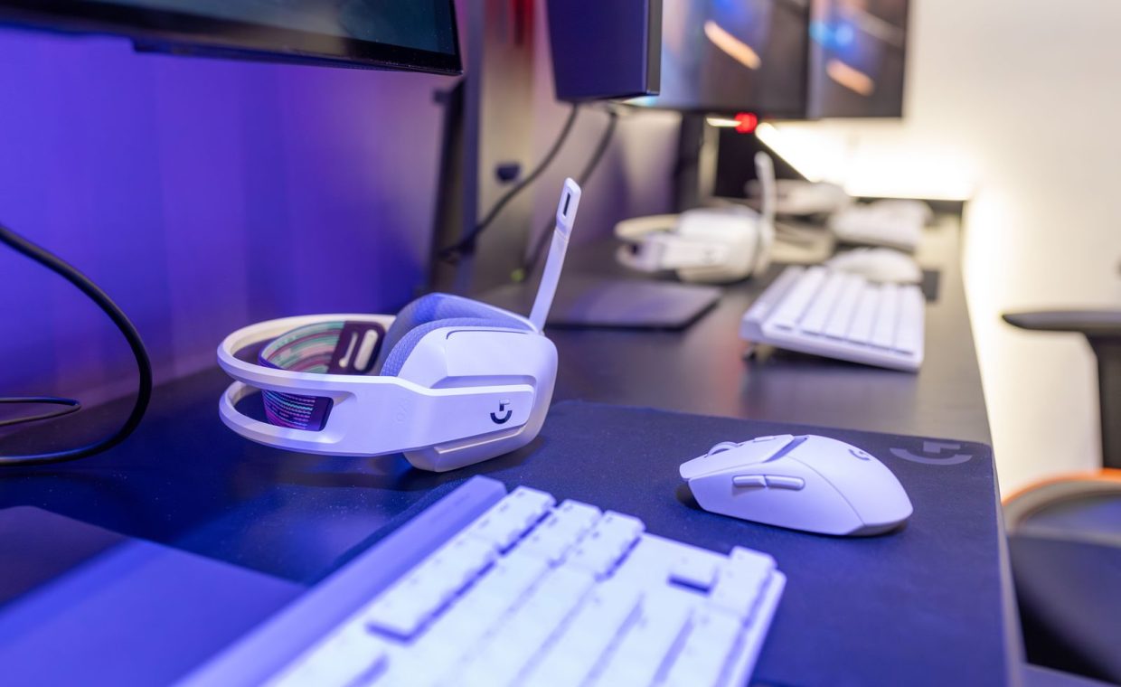 Close-up of a gaming setup featuring a white headset, computer mouse, and keyboard with a vivid lighting ambiance.