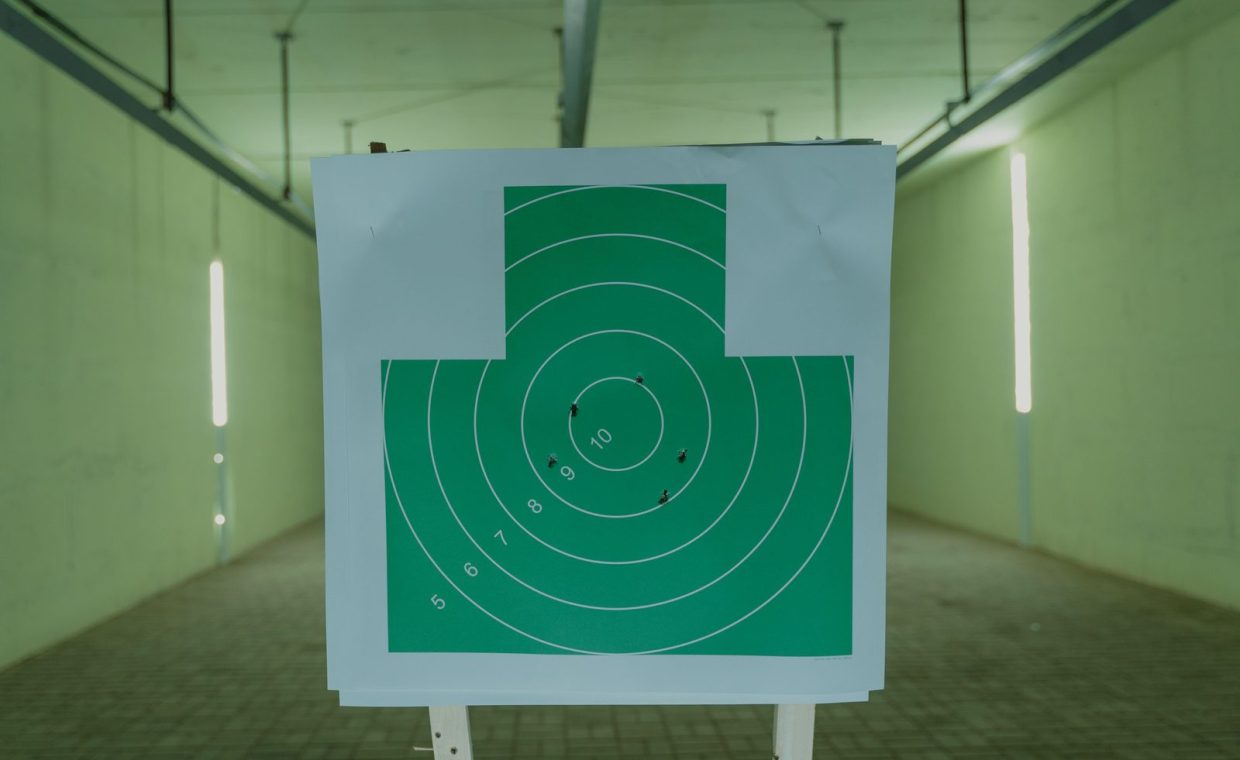 A green circle target with bullet holes at an indoor shooting range, ideal for practice visuals.