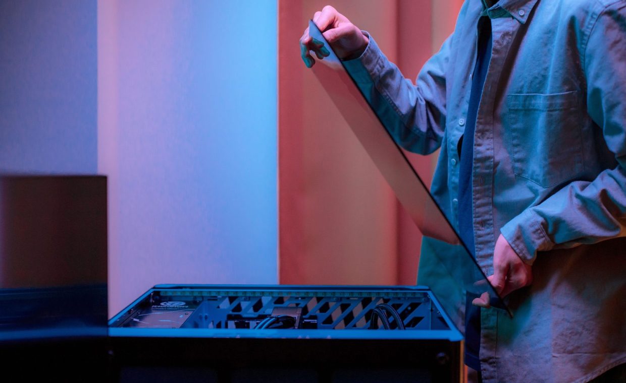 A man carefully fits a glass panel onto a gaming PC while adjusting internal cables.