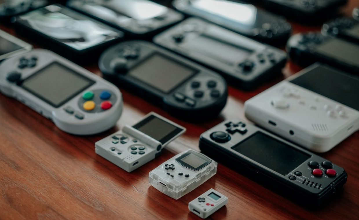 Collection of diverse retro handheld gaming consoles on a wooden surface, showcasing classic designs and nostalgia.