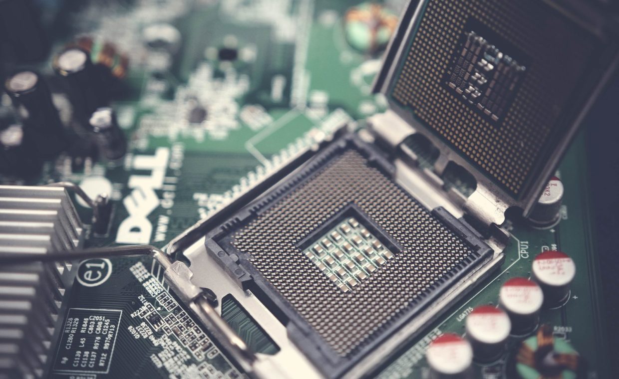 Detailed close-up shot of a computer motherboard featuring an open CPU socket and electronic components.
