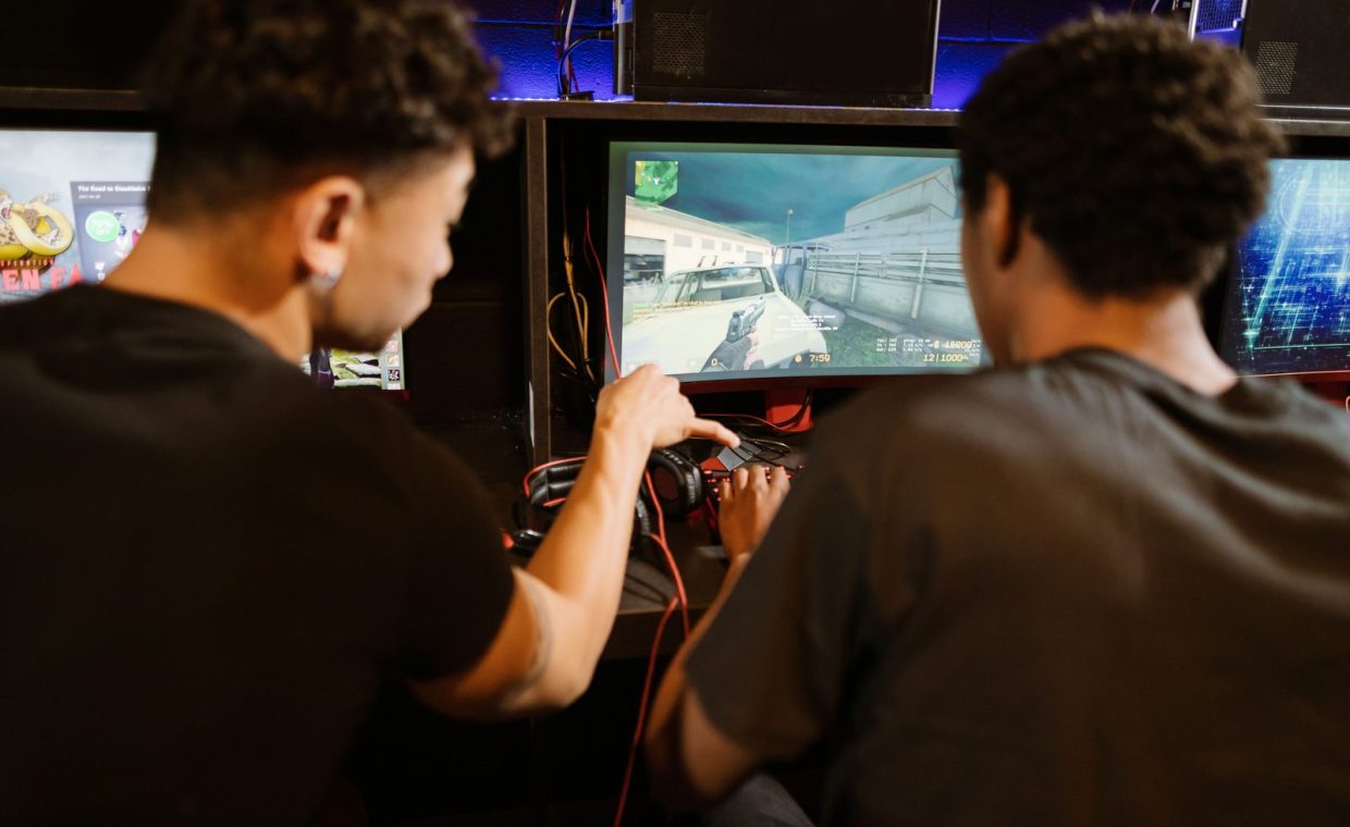 Two young men playing a multiplayer computer game at an arcade with enthusiasm and focus.
