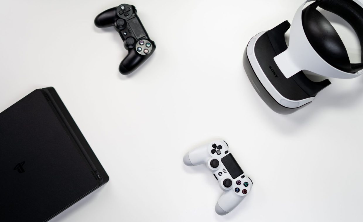 Flat lay of gaming console, controllers, and VR headset on a white background.
