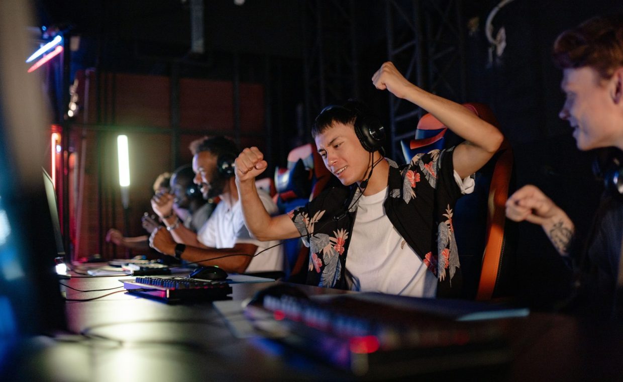 Excited gamers celebrating a win in a competitive gaming tournament with headphones.