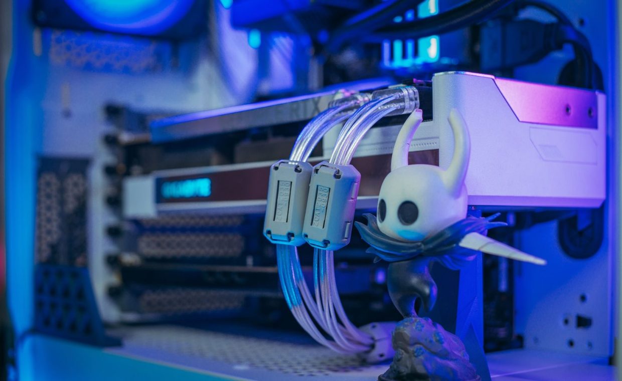 Close-up shot of a custom gaming PC with liquid cooling and figurine under blue lighting.