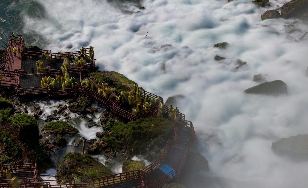 People stand near niagara falls' roaring water.